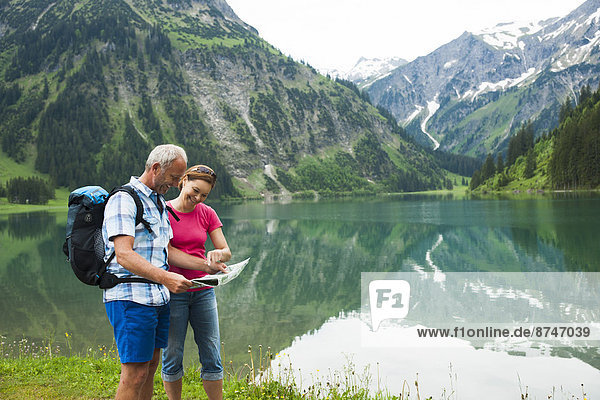 Mature couple looking at map  hiking in mountains  Lake Vilsalpsee  Tannheim Valley  Austria