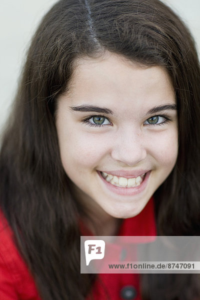 Close-up Portrait of pre-teen girl with long  brown hair  smiling and looking at camera