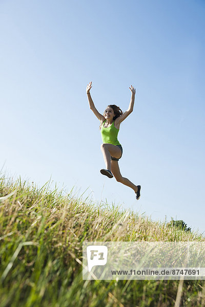 Teenaged girl jumping in mid-air in field  Germany