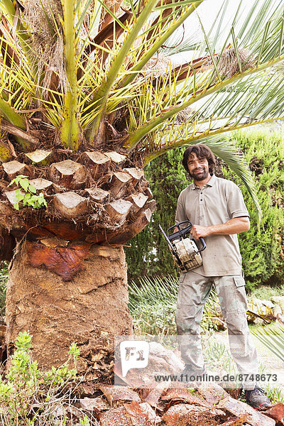 Portrait of man holding chainsaw for peeling palm tree  Majorca  Spain