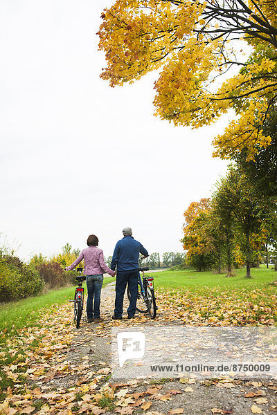 Couple Walking Bicycles on Path in Autumn  Mannheim  Baden-Wurttmeberg  Germany