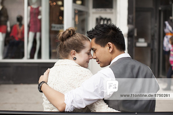 Close-up  backview of couple sitting on bench on city street  Toronto  Ontario  Canada