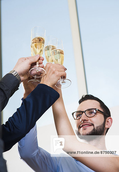 Business people holding champagne glasses and toasting each other in office  Germany