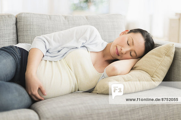 Pregnant Japanese woman napping on sofa
