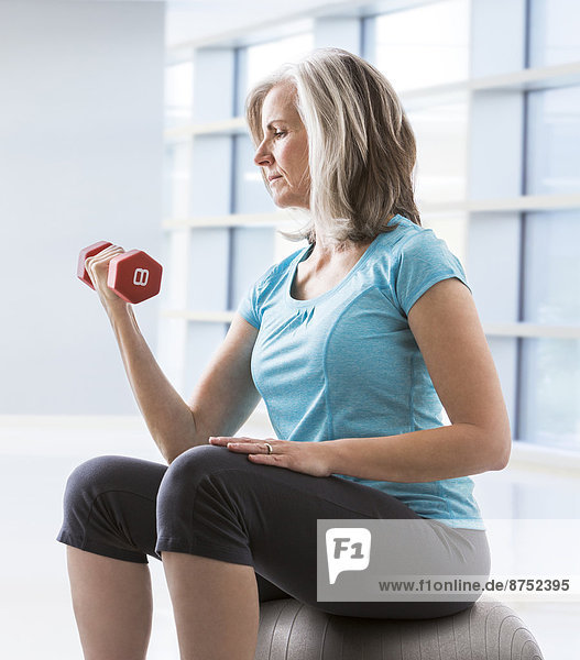 Caucasian woman doing biceps curls with dumbbell