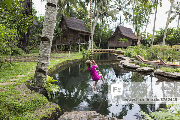 Caucasian girl swinging on rope in garden  Ubud  Bali  Indonesia