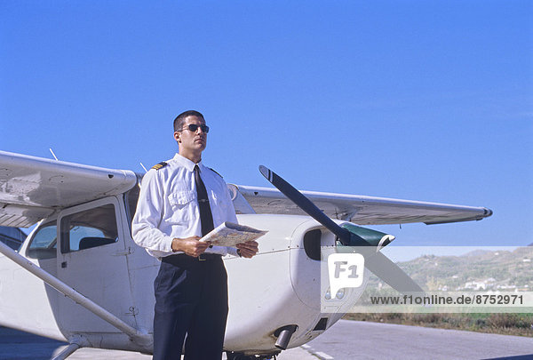 Pilot hält eine Karte und ein Propellerflugzeug Private einstehen