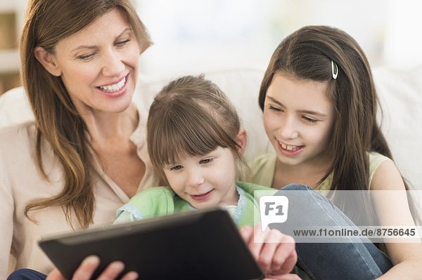Mother and daughters (4-5 8-9) using tablet pc