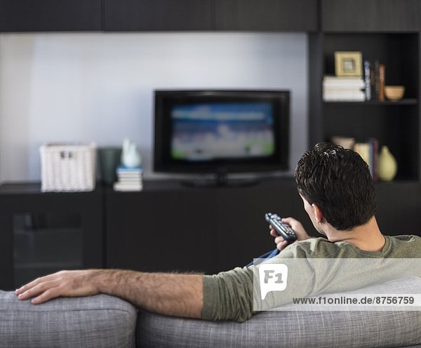 Rear view of man watching tv
