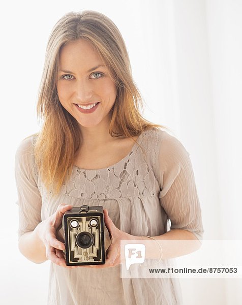 Portrait of young woman holding vintage camera