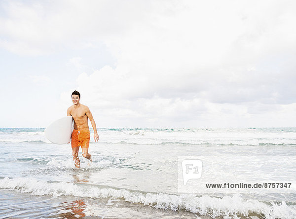 Young man carrying surfboard