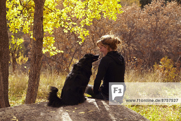 Woman and her collie sitting on stone