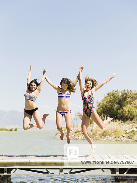 Three women jumping into lake