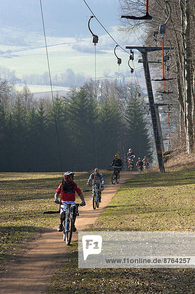 Mountain bikers are pulled by a ski lift  Osternohe  Bavaria  Germany