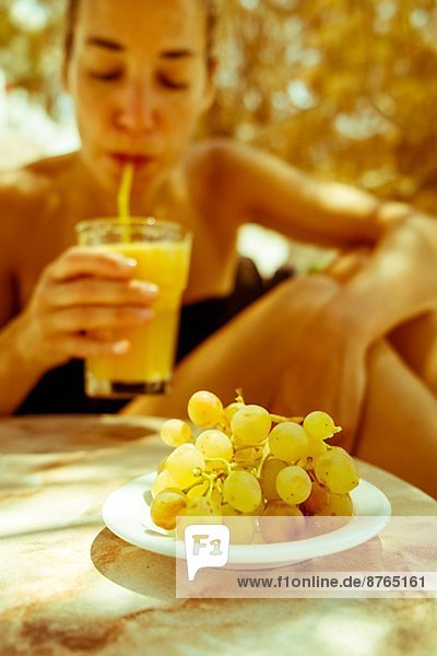 Woman drinking juice  grapes on foreground