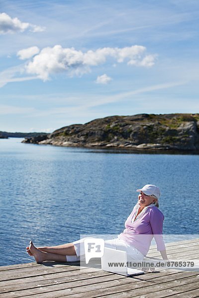 sitzend  Senior  Senioren  Frau  lächeln  Steg  Bohuslän  Schweden