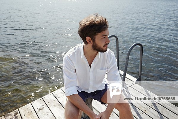 Young man sitting on jetty  Sweden