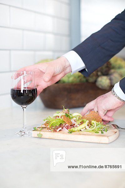 Hands with glass of wine and food