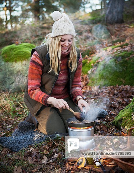 Mature woman frying mushrooms in forest  Sweden