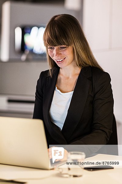 Smiling young woman working on laptop in office  Stockholm  Sweden