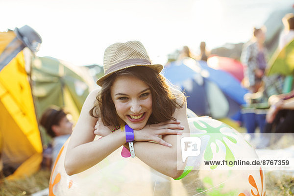 Porträt einer lächelnden Frau  die sich auf einem aufblasbaren Stuhl vor den Zelten des Musikfestivals stützt.