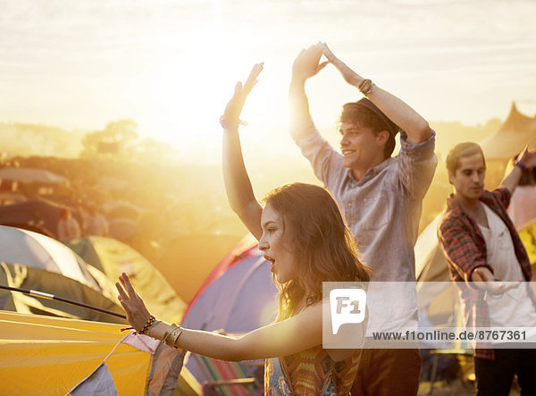 Freunde tanzen außerhalb der Zelte beim Musikfestival