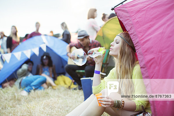 Frau bläst Blasen aus dem Zelt beim Musikfestival