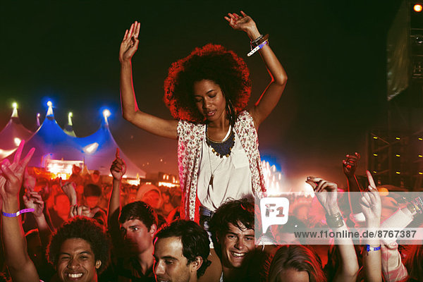 Cheering woman on manÍs shoulders at music festival