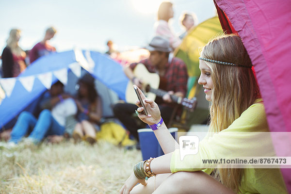Frau SMS mit Handy im Zelt beim Musikfestival