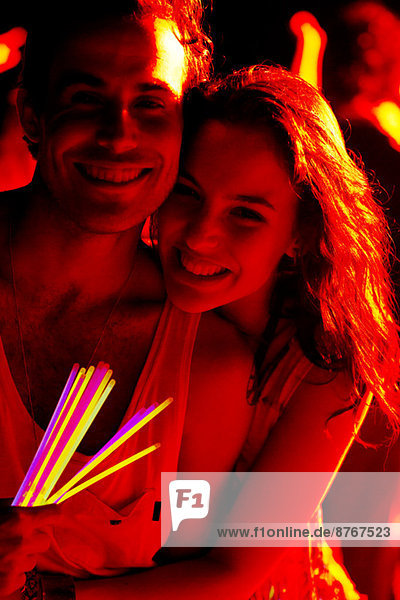 Nahaufnahme Porträt eines glücklichen Paares mit Leuchtstäben beim Musikfestival
