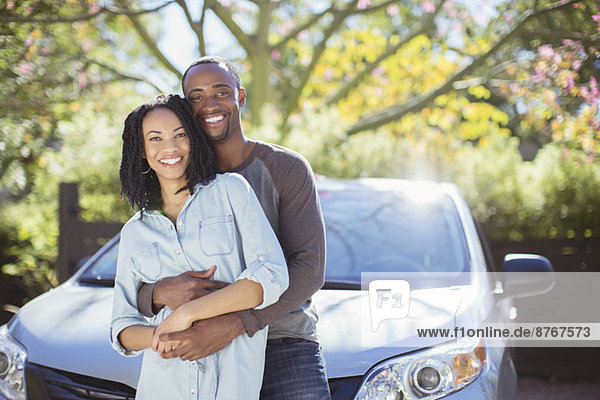 Porträt eines glücklichen Paares  das sich außerhalb des Autos umarmt.