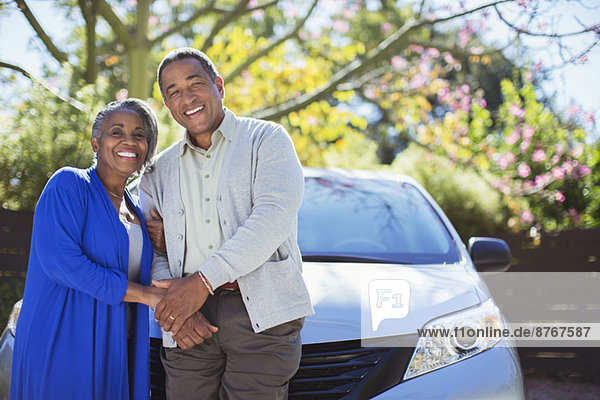 Porträt eines glücklichen älteren Paares  das sich auf das Auto stützt.
