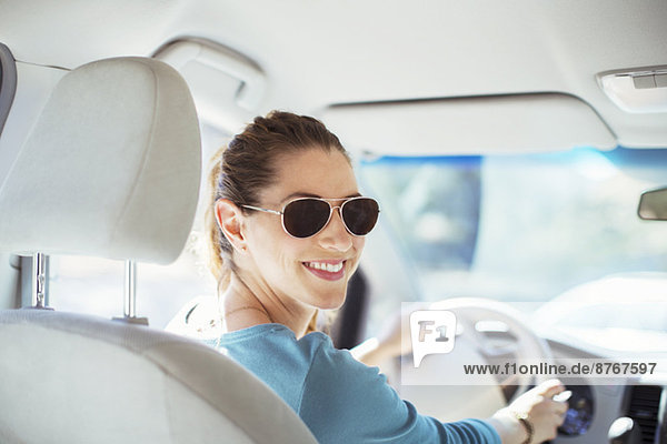 Porträt einer selbstbewussten Frau mit Sonnenbrille beim Autofahren