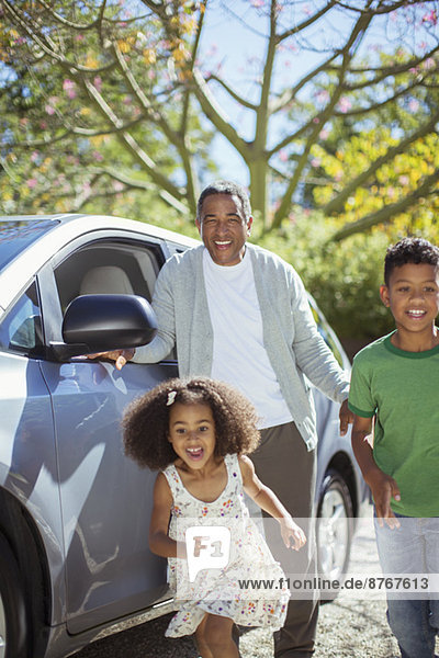 Enthusiastic grandfather and grandchildren running outside car