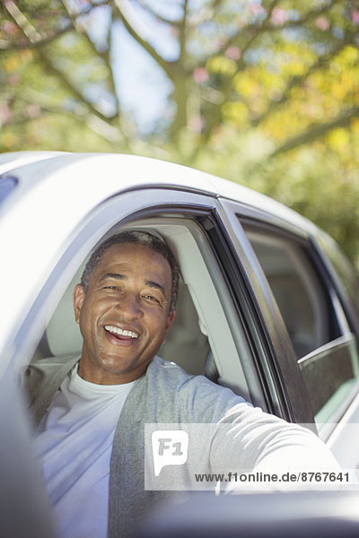 Porträt eines älteren Mannes  der im Auto lacht