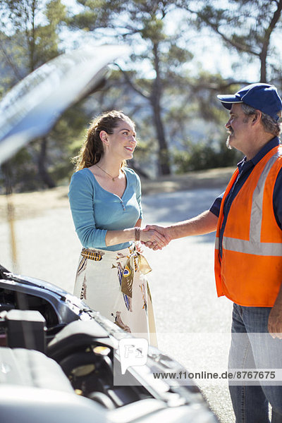 Frau schüttelt sich die Hand mit dem Mechaniker am Straßenrand