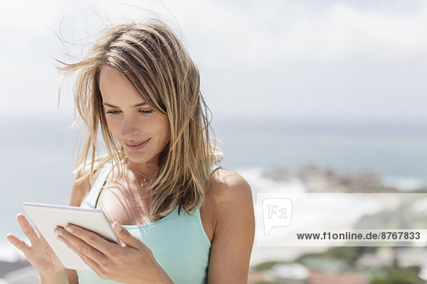 Woman using digital tablet with ocean in background