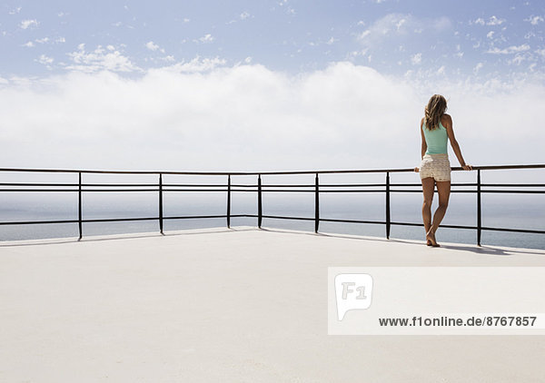 Woman standing on balcony overlooking ocean