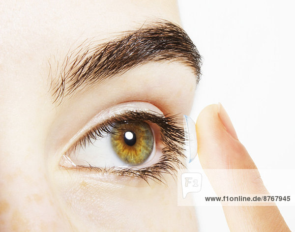 Extreme close up of woman putting contact lens into eye