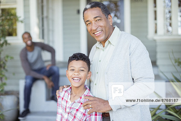 Porträt des lächelnden Großvaters und Enkels vor dem Haus