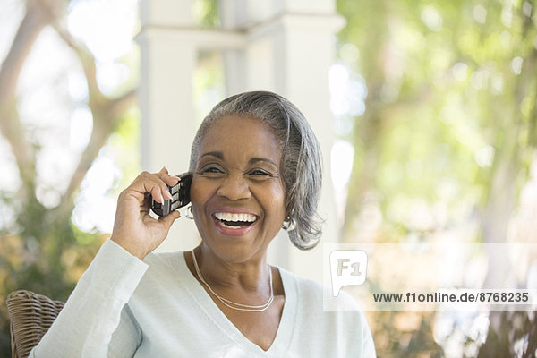 Enthusiastische Seniorin am Telefon auf der Veranda