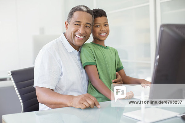 Porträt des lächelnden Großvaters und Enkels am Computer