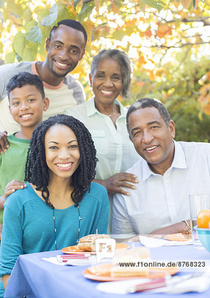 Porträt der lächelnden Mehrgenerationen-Familie beim Mittagessen auf der Terrasse
