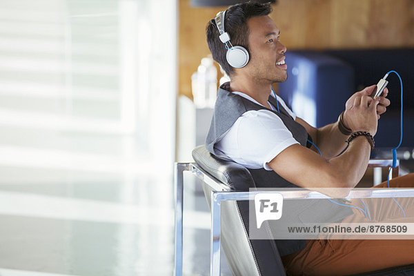 Lächelnder Geschäftsmann hört Musik auf mp3-Player mit Kopfhörer