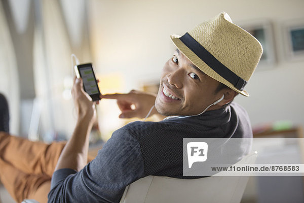 Porträt eines selbstbewussten Mannes in Fedora beim Musikhören über Kopfhörer mit mp3-Player