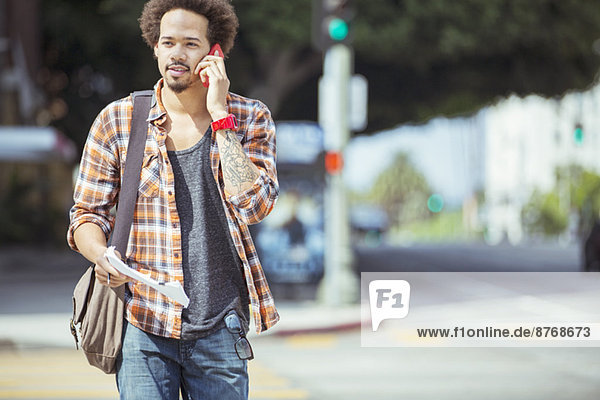 Man talking on cell phone in urban crosswalk