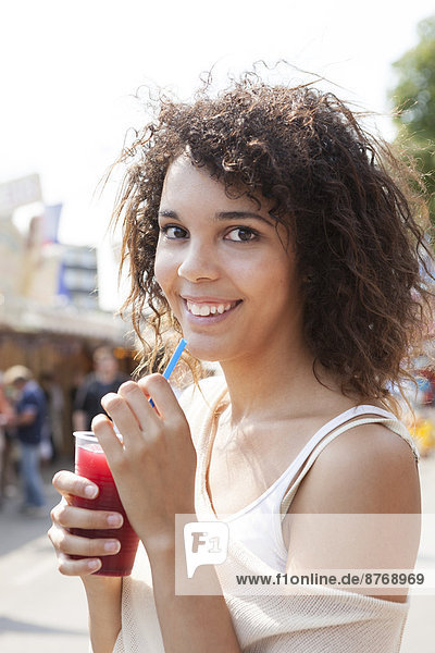 Junge Frau auf dem Jahrmarkt trinkt Saft  Porträt