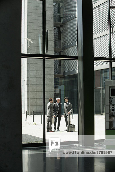 Drei Geschäftsleute vor dem Bürogebäude