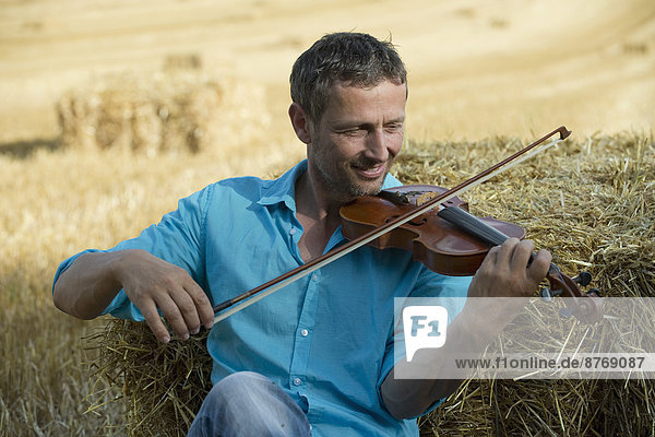 Porträt des Mannes im Stoppelfeld beim Geigenspiel