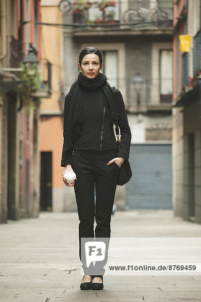 Spanien  Katalonien  Barcelona  junge  schwarz gekleidete Geschäftsfrau mit Kaffee vor der Strasse